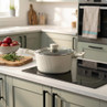 Cream casserole pot with lid on induction hob in modern kitchen