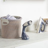 Handheld garment steamer in blue and white on laundry counter next to iron and basket of clothes