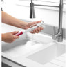Bottle cleaning brush with pink handle washing a glass bottle at the sink