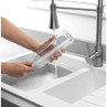 Bottle cleaning brush scrubbing clear bottle under running tap in kitchen sink
