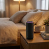 Black smart speaker with purple light ring on bedroom table