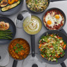 Grey non-stick cookware set with assorted meals, shown from above.