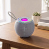 Blue wireless portable speaker with LED light on top, placed on a wooden table