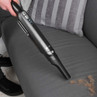 Handheld silver vacuum cleaning pet hair from grey sofa seat
