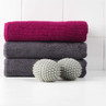 Folded pink and grey towels with two white laundry balls in front, for home and bath use