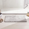 Light grey chevron bath mat on bathroom floor, shown beside towels and slippers
