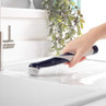 Electric cleaning brush scrubbing white kitchen sink near tap