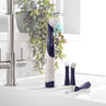Electric cleaning brush with navy and white handle plus three brush heads on kitchen sink