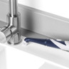 Blue and white electric cleaning brush on kitchen worktop beside stainless steel tap