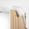 Extendable white duster cleaning the top of a wooden door