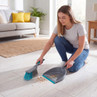 Grey and blue dustpan and brush set collecting crumbs from light wood floor