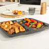 Oven tray with roast potatoes and mixed vegetables on kitchen worktop