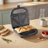 Electric sandwich maker with two toasted sandwiches, shown in modern kitchen setting