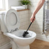 Black toilet brush cleaning a white toilet in a modern bathroom