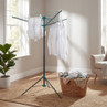 Indoor rotary clothes airer with white shirts drying, wicker laundry basket nearby