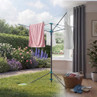 Rotary clothes dryer showing indoor and outdoor use, with towels and laundry basket