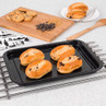 Four chocolate chip brioche rolls on a baking tray, cooling on a kitchen worktop