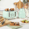 Mint green 4-slice toaster and kettle set on kitchen counter with bread and breakfast.