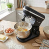 Black stand mixer with beater, mixing flour, butter and eggs in a kitchen setting