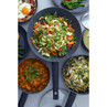 Three non-stick pans with colourful vegetable stir fry, pasta, and curry