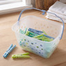 Plastic basket with blue handle filled with green and blue pegs, two pegs on worktop