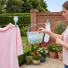 Plastic peg basket with pastel pegs in use outdoors, on laundry line with clothes.