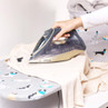 Hand using Beldray iron on cream shirt on dog print ironing board