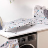 Mini ironing board with grey dog print cover on laundry room counter