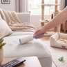 Lint roller removing pet hair from light grey sofa in a pet-friendly living room