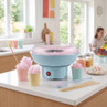 Blue candyfloss maker on kitchen counter with pink candyfloss in paper cups
