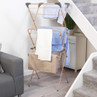 Foldable indoor clothes airer with grey accents holding shirts and towels.