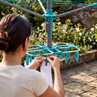 Person hanging socks on blue rotary airer with peg rack outdoors, close up