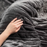 Hand touching soft grey ribbed throw blanket
