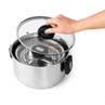 Stainless steel stock pot with glass lid, shown being removed by hand.