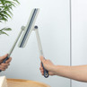 Flexible blue and grey squeegee cleaning a mirror