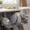 Open dishwasher with clean plates, glasses and cutlery in a modern kitchen setting