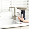 Hand holding window vacuum water tank at kitchen sink, showing how to empty or refill