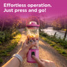 Pink portable blender with fruit inside, being activated outdoors on a path.