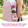 Portable pink blender with fruit and veg in backpack side pocket, outdoor setting