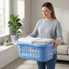 Blue plastic laundry basket with folded towels, held by person in grey jumper indoors