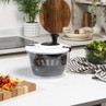 Clear plastic salad spinner with black handle on kitchen counter