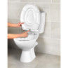 Close-up of hands demonstrating quick release button on white toilet seat.