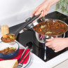 Serving stew with vegetables from saucepan to bowl on induction hob
