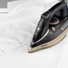 Steam iron in use on grey shirt to show wrinkle removal