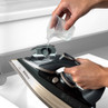 Person pouring water into steam iron at a sink