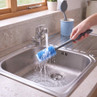 Blue silicone washing-up brush being rinsed under a kitchen tap
