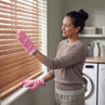 Pink cleaning gloves used to dust wooden blinds in laundry room