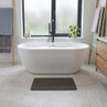 Charcoal bath mat on tiled bathroom floor in front of white freestanding bath