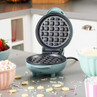 Teal mini waffle maker open on a kitchen counter, shown ready for use.