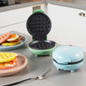 Mini waffle makers in mint and blue with plated waffles in a modern kitchen